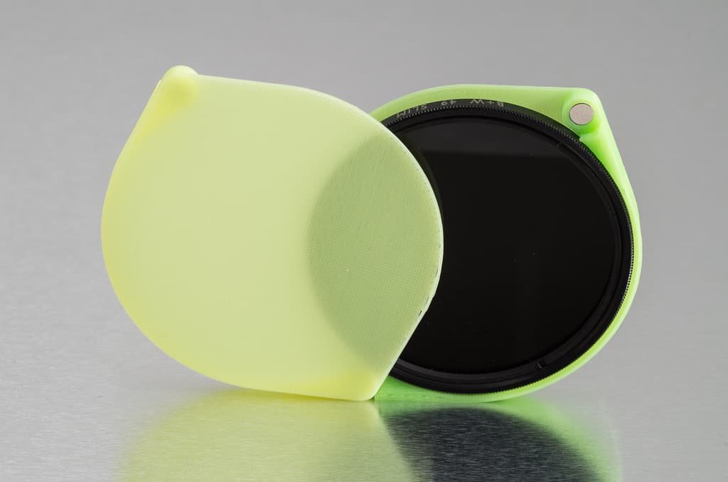 Lens filter case, open, holding a round filter